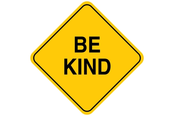 Yellow diamond shaped sign with the letters BE Kind on it in black